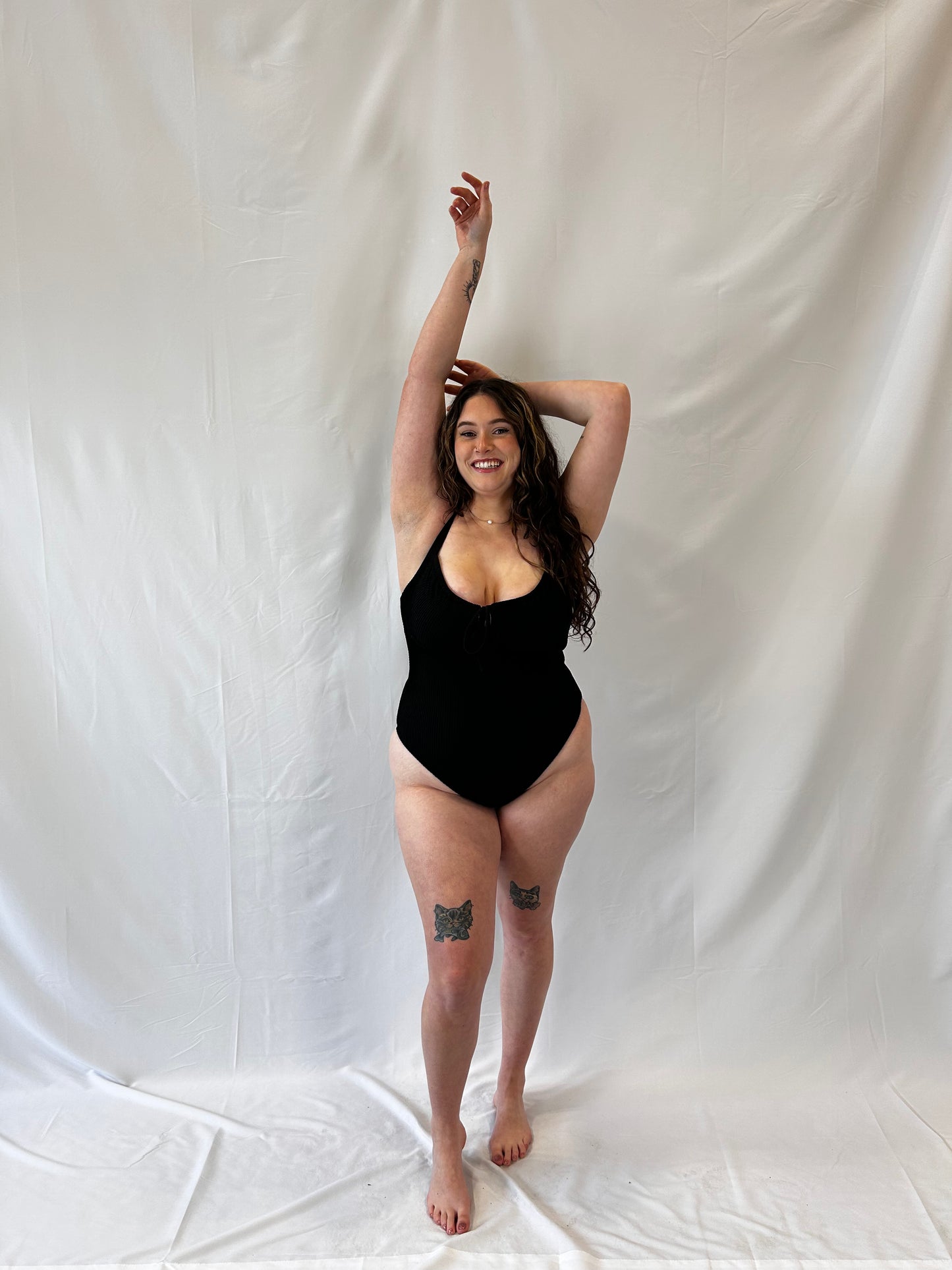 Model wears the black one piece. Model wears the milkmaid style tie front crinkle fabric one piece. Black one piece is high cut and cheeky.