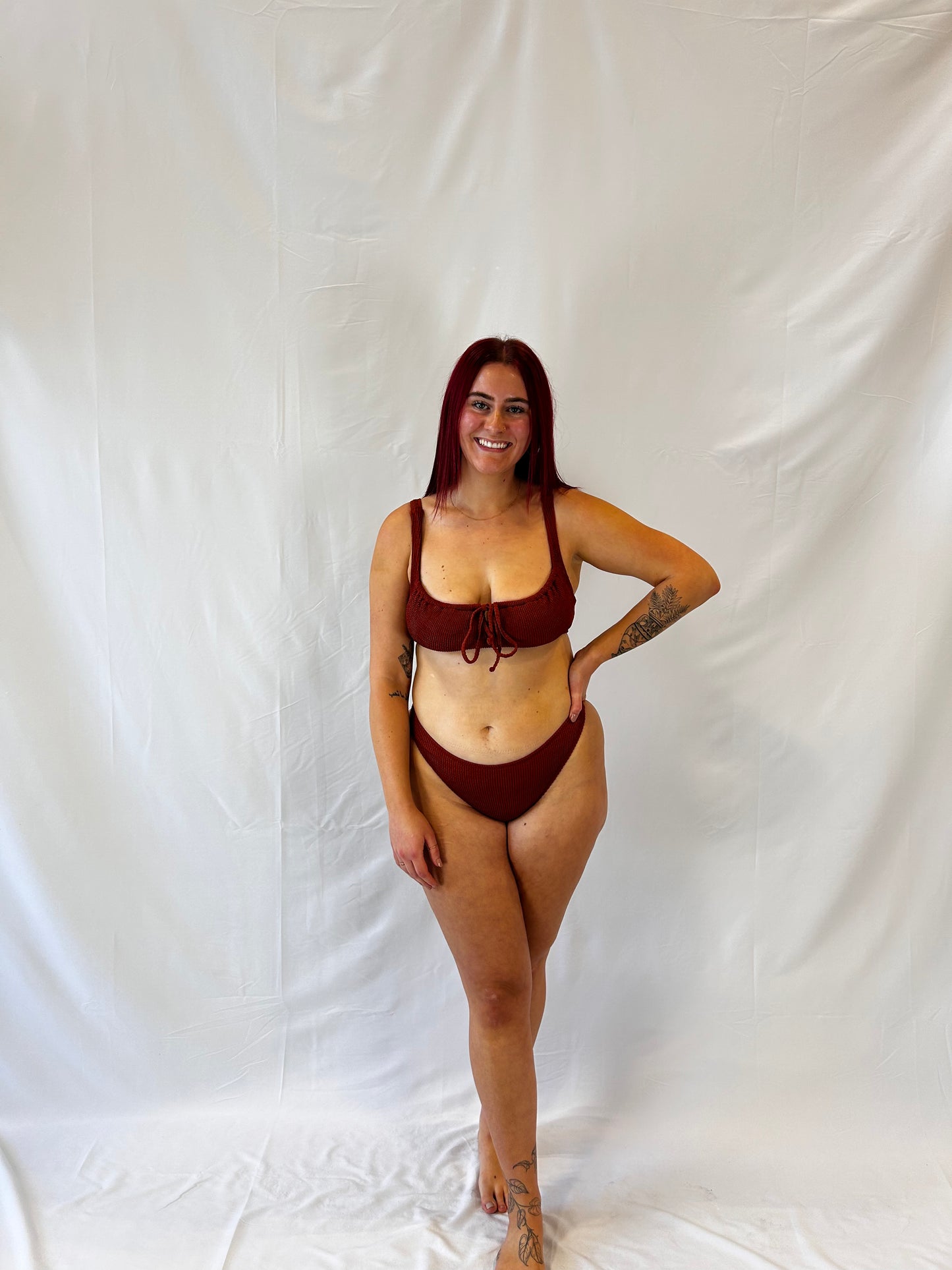 Model wears the two piece bikini in rust. Bikini top is the milkmaid style tie front crinkle fabric. Bikini bottom is the high rise cheeky textured crinkle fabric.