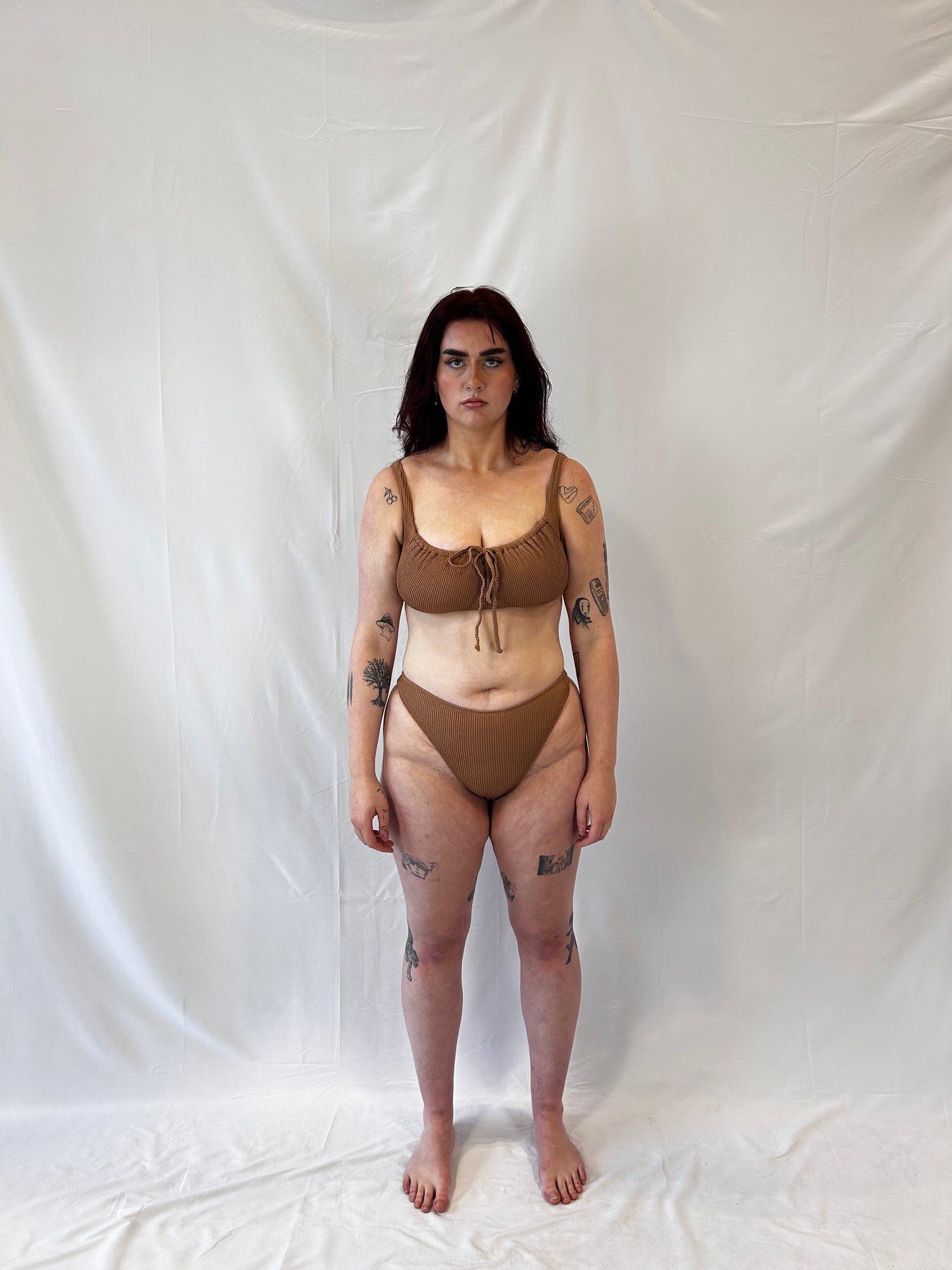 Model wears the milkmaid style tie front crinkle fabric bikini top. Model wears the high rise cheeky textured crinkle fabric bikini bottom in beige.