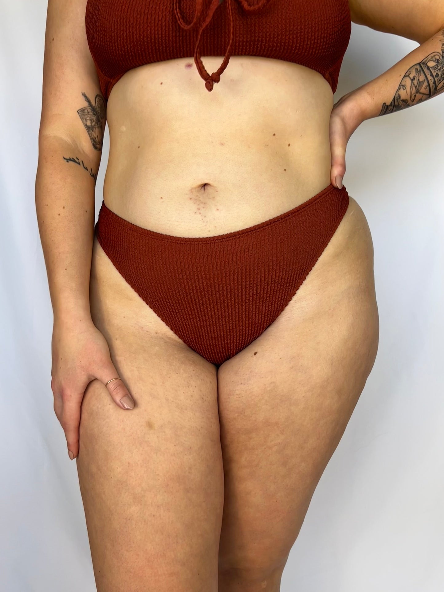 Close up of the rust bikini bottom from the front. Model wears the high rise cheeky textured crinkle fabric bikini bottom.