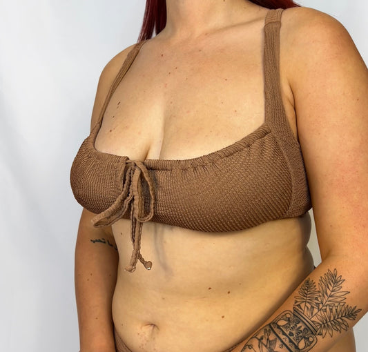 Close up of the two piece bikini top in beige. Model wears the milkmaid style tie front crinkle fabric bikini top.