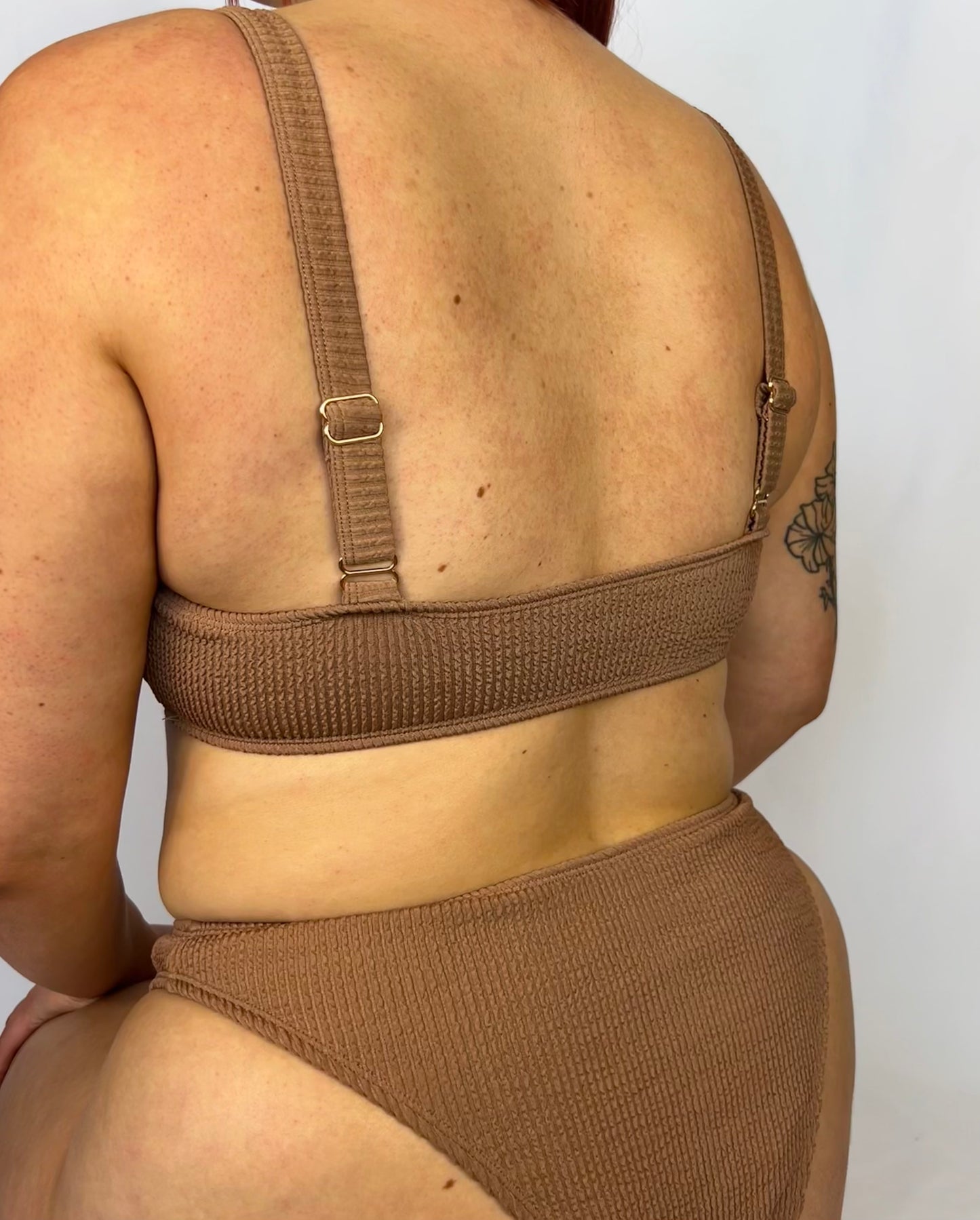Close up of the two piece bikini top in beige from the back. Model wears the milkmaid style tie front crinkle fabric bikini top.