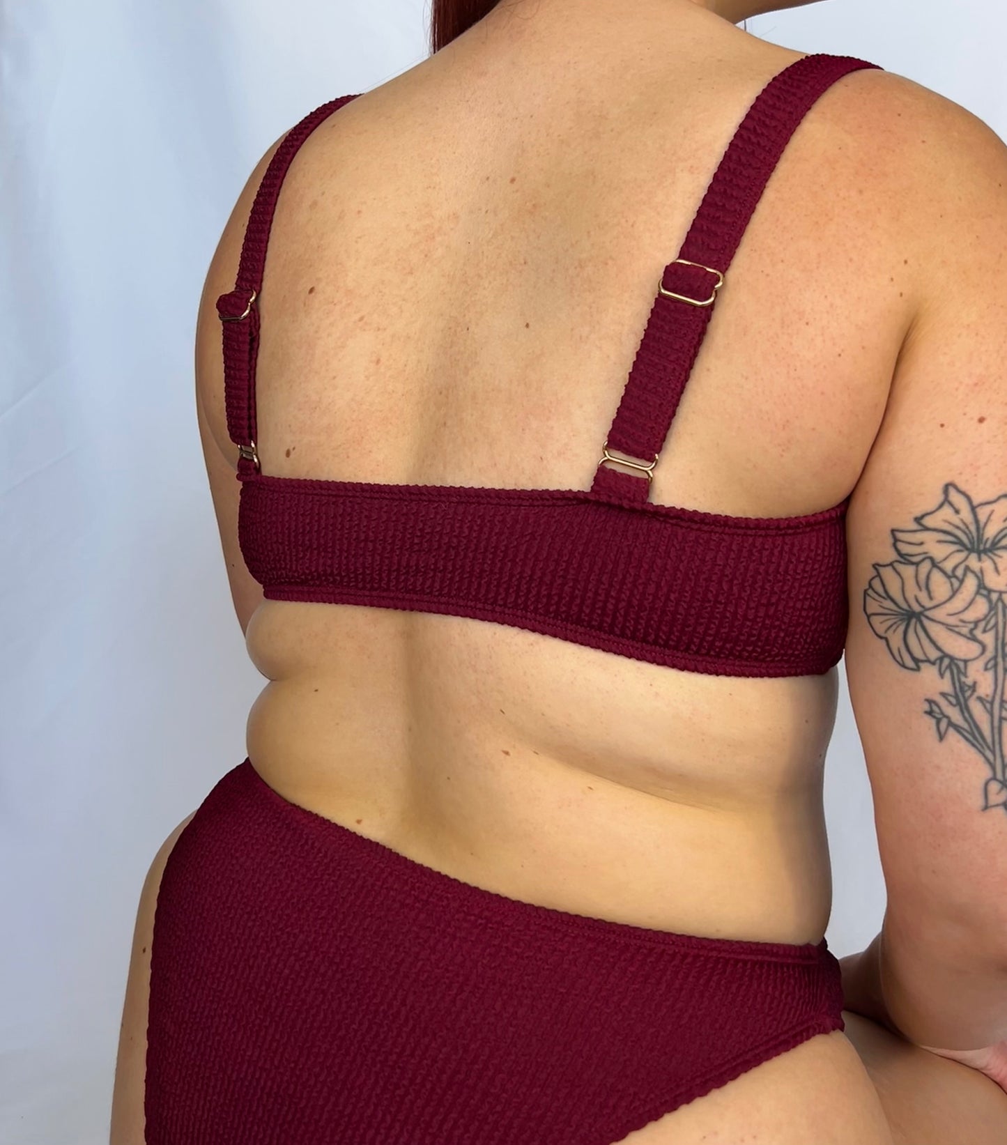 Close up of the two piece bikini top in burgundy from the back. Model wears the milkmaid style tie front crinkle fabric bikini top.