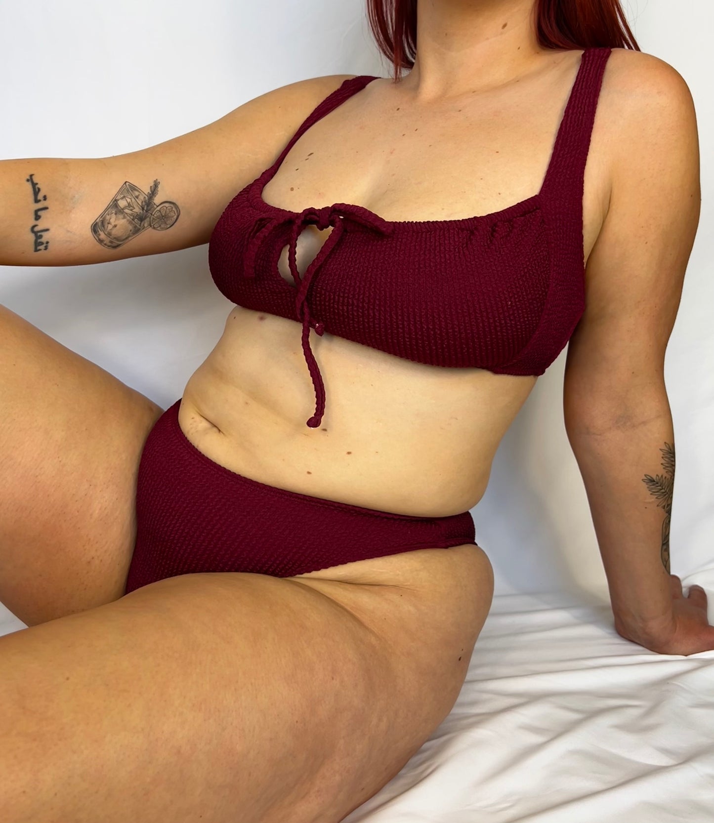 The two piece bikini from the front in burgundy. Model wears the milkmaid style tie front crinkle fabric bikini top.
