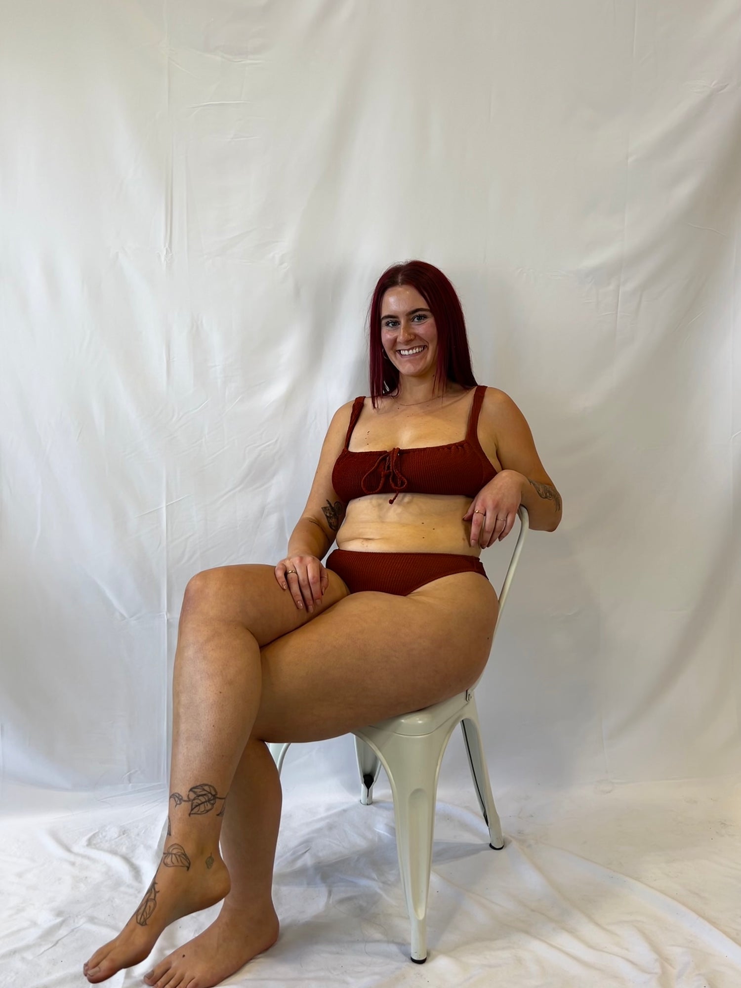 Founder sitting in a chair in the rust two piece bikini
