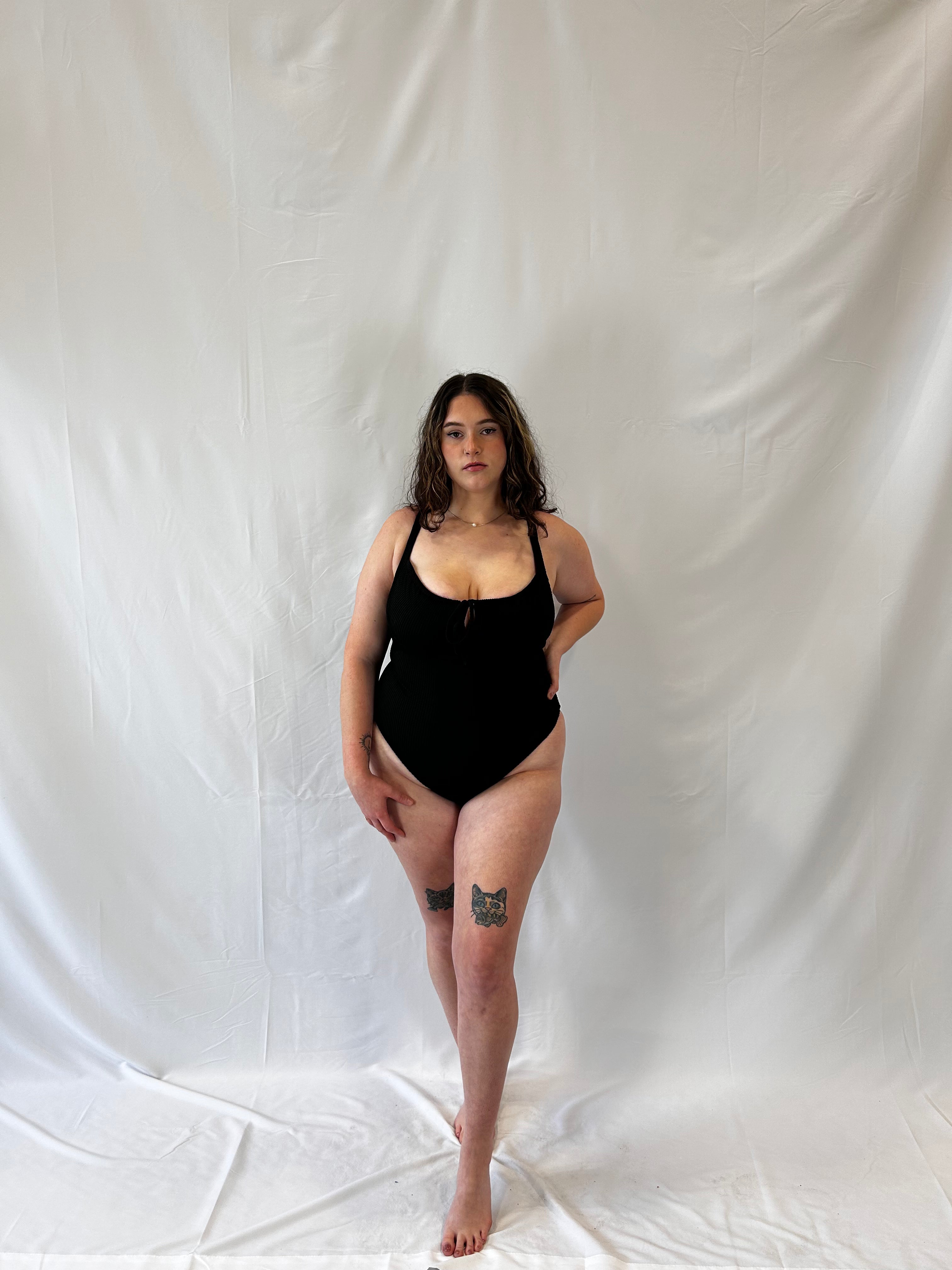 Model wears the black one piece. Model wears the milkmaid style tie front crinkle fabric one piece. Black one piece is high cut and cheeky. 
