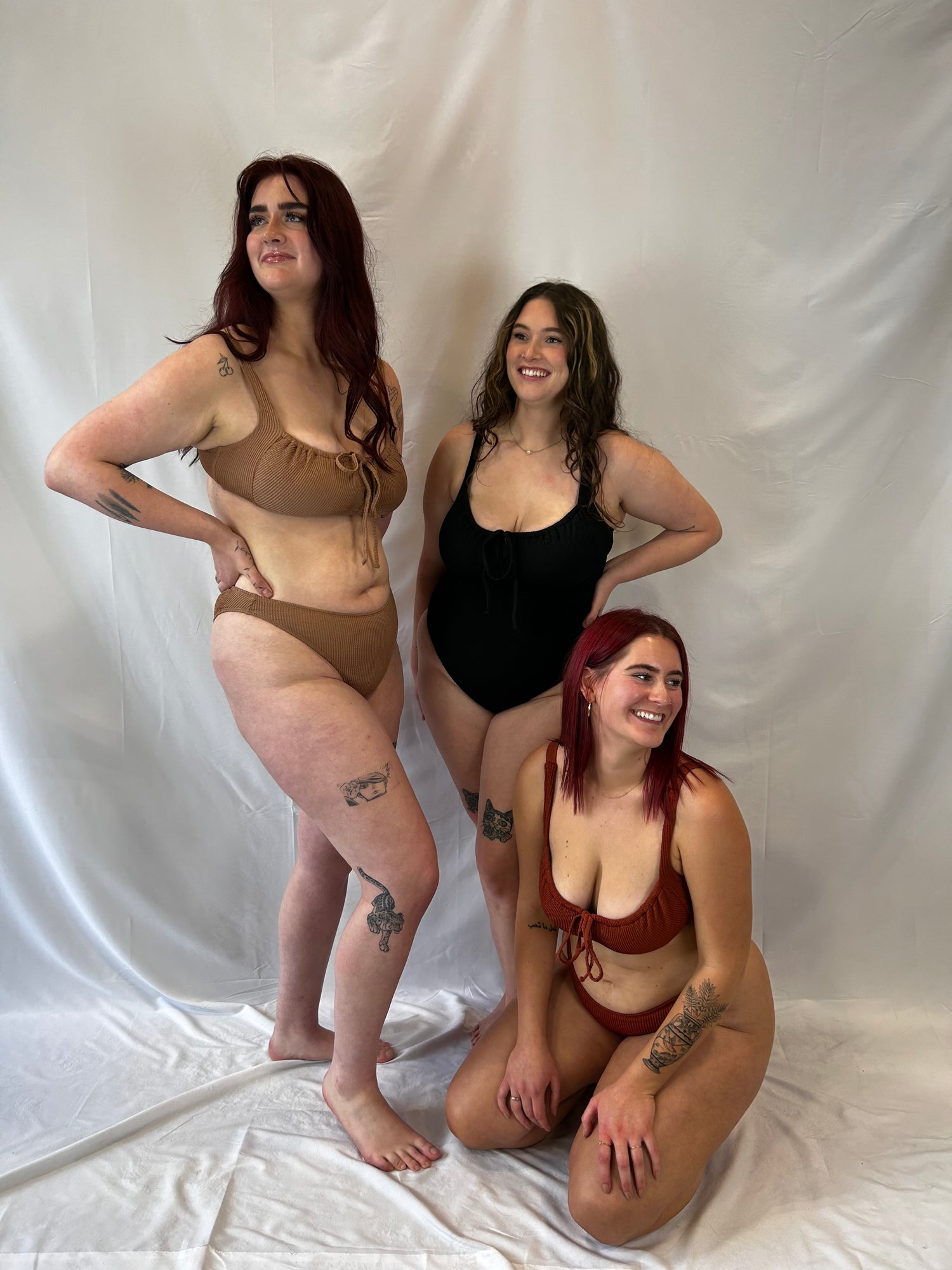 Models representing sizes XL and XXL in the beige bikini, black one piece, and rust bikini.