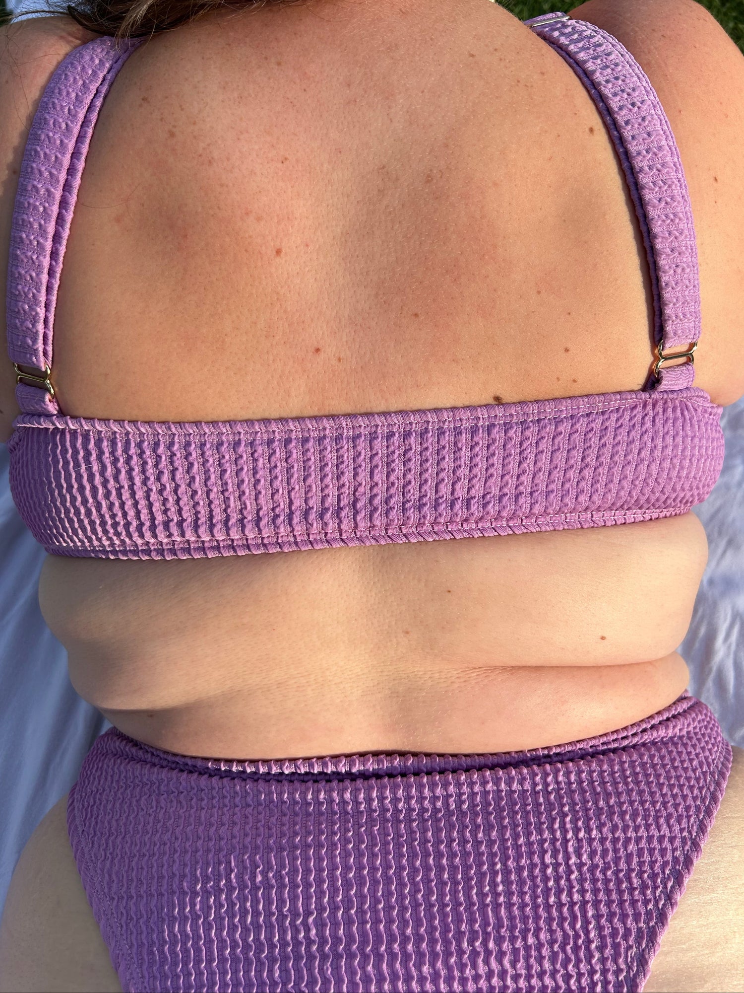 Lavender bikini top worn by a person, with a close-up view of the straps and fabric.